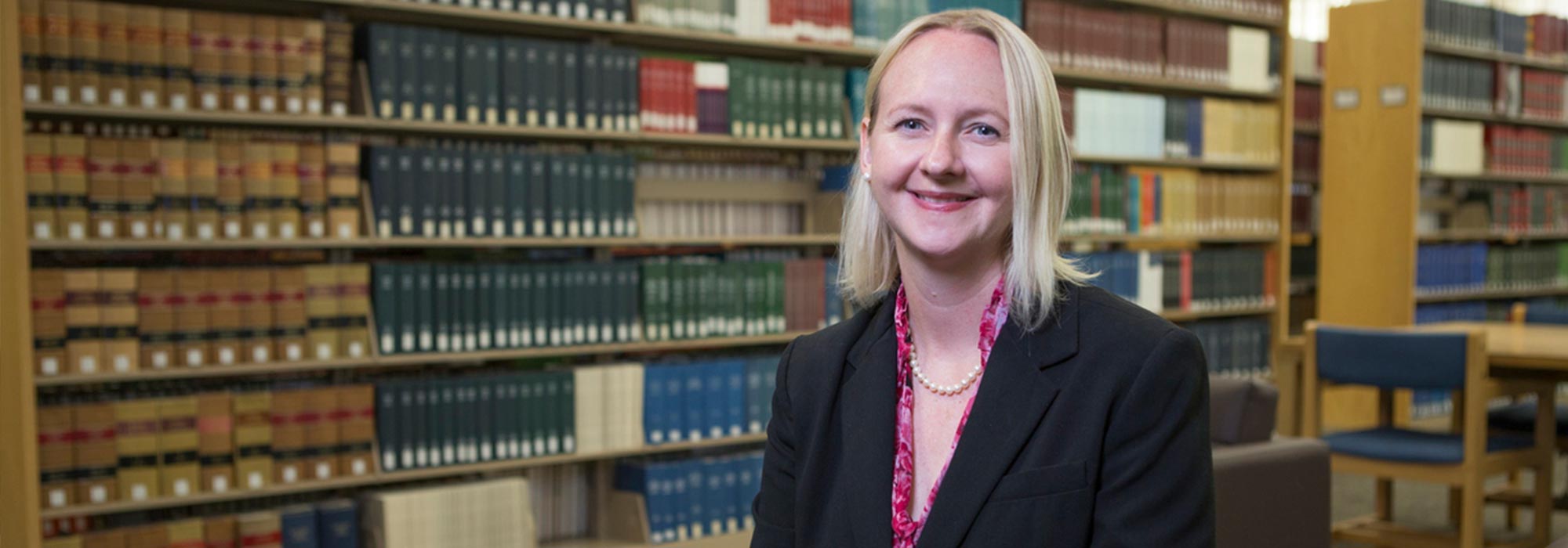 NIU professor seated in a library with bookshelves in the background