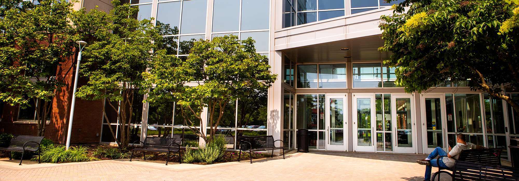 Modern building entrance in Naperville with glass windows, trees and benches.